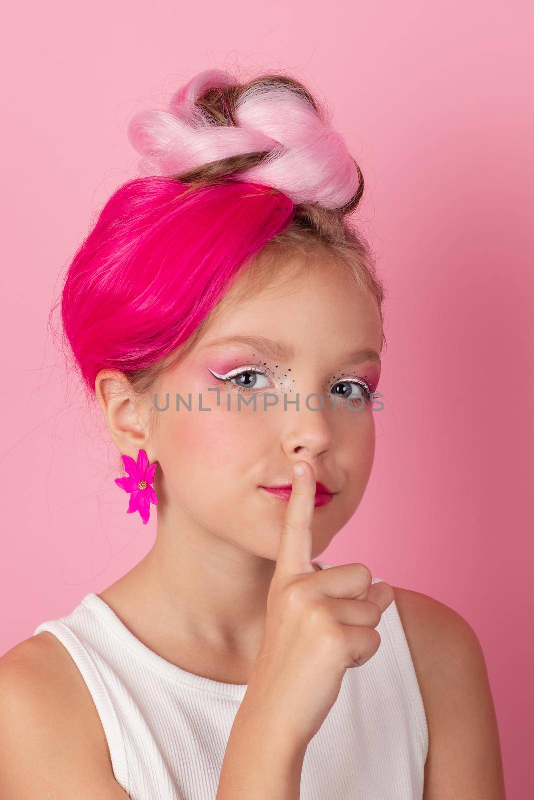 charming little girl with pink hairstyle and pink makeup. tween young model posing on pink background.