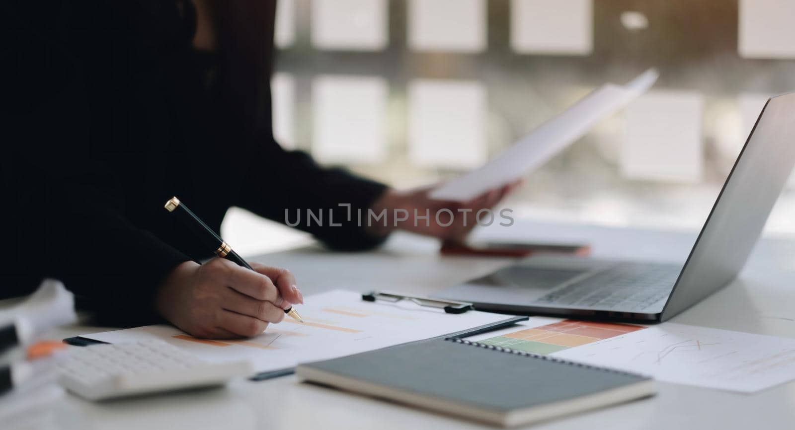 Close up of businesswoman or accountant hand holding pen working on business financial data, accountancy document and calculator at office. by wichayada