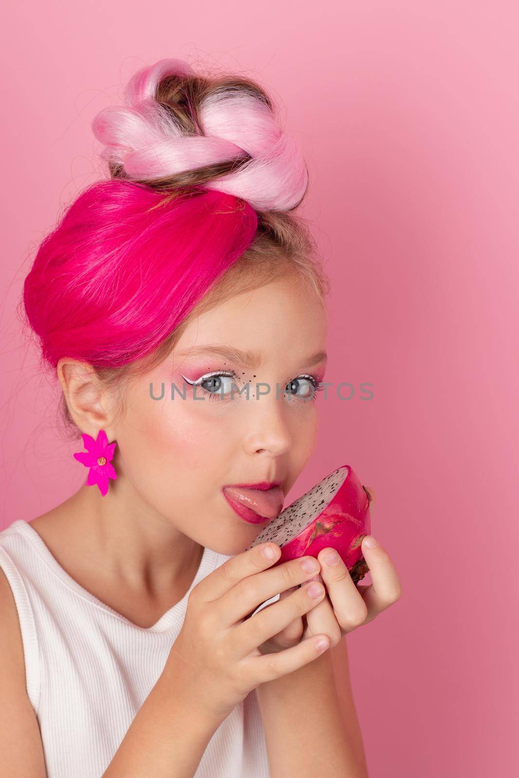 sweet Girl is holding a Pitahaya near her face. A pitaya fruit hold in hand on pink background. Tropical Dragon Fruit cut in half. space for text