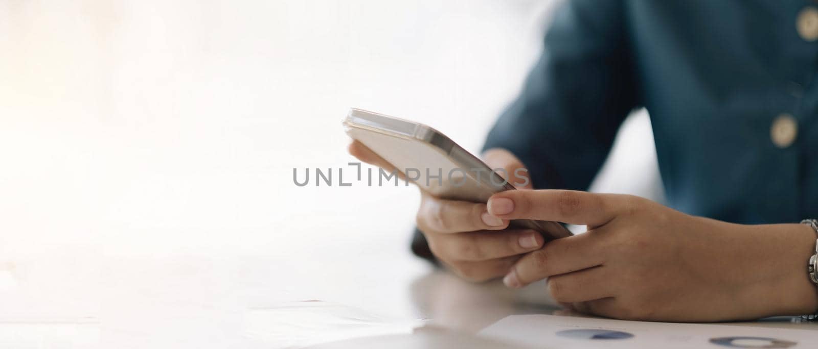 Close up hand of woman using smartphone at office.