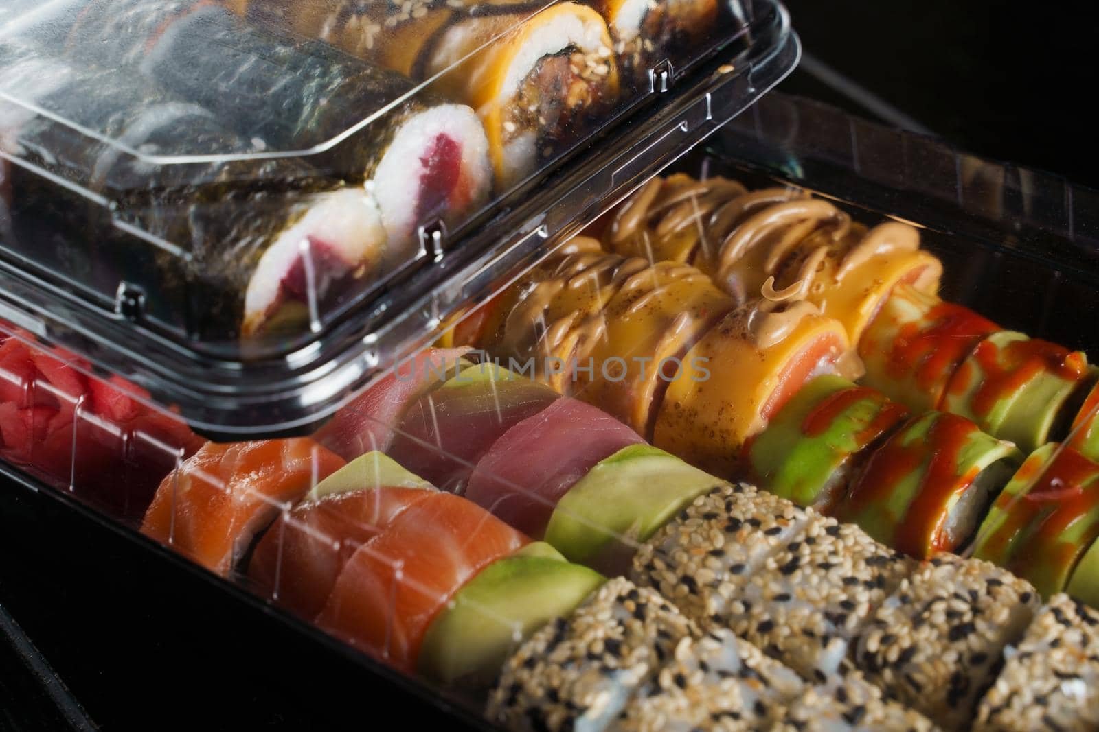 Sushi roll food delivery service. Sushi set in box on black background. Traditional Japanese seafood. Delicious roll.