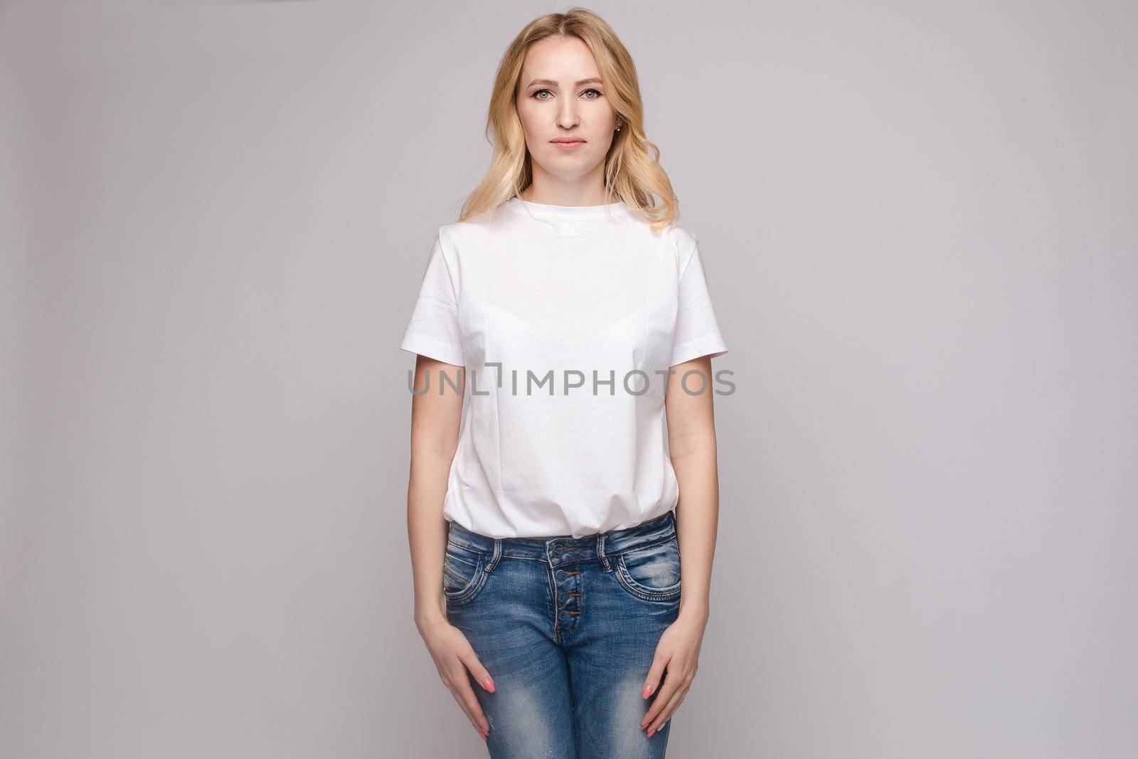 Slim woman wearing white shirt and jeans standing steady by StudioLucky