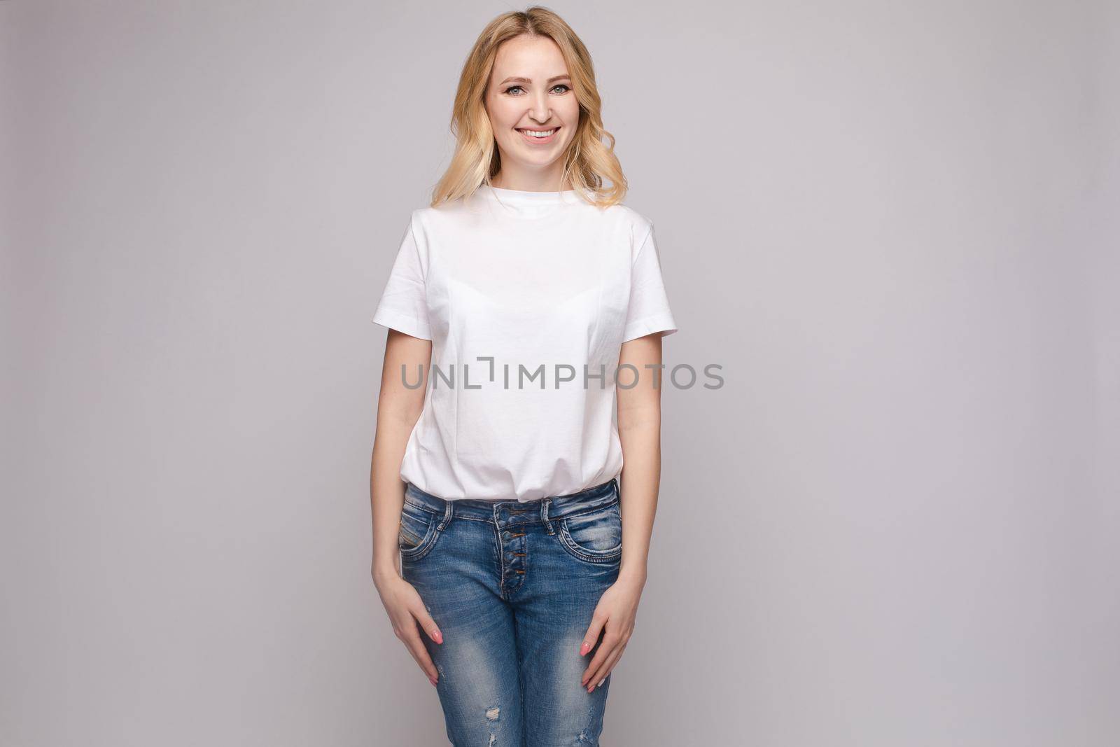 Slim woman wearing white shirt and jeans standing steady by StudioLucky