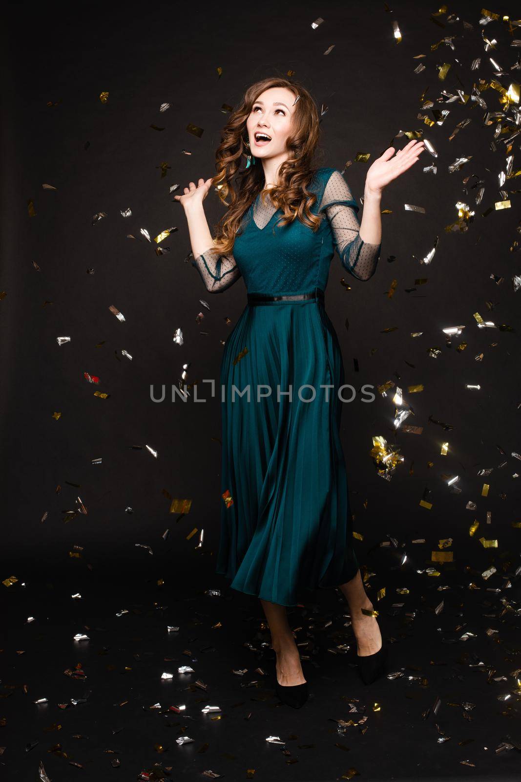 Happy young girl looking surprisingly while golden confetti falling. by StudioLucky