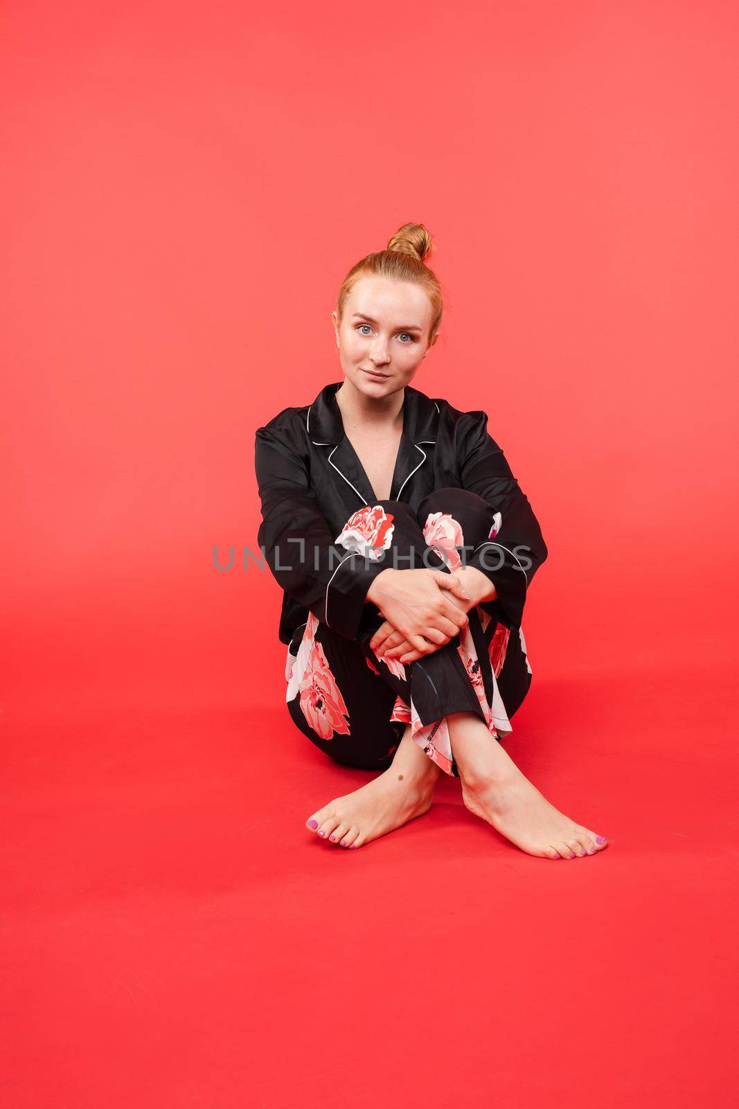 Young girl in black pijama sitting on floor and meditating with closed eyes. Beautiful happy woman in casual clothes doing yoga and practicing breathing. Pretty relaxed lady caring about her health.