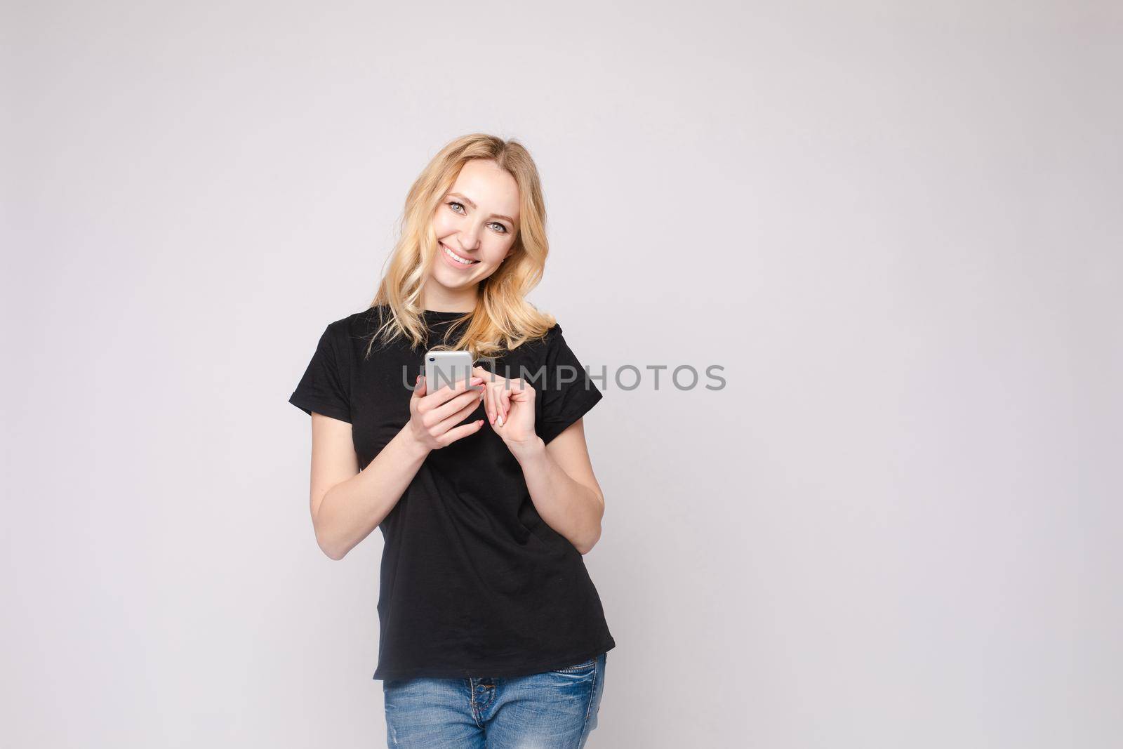 Studio portrait of beautiful caucasian brunette woman in patterned overall pointing at her smartphone with index finger. She is certain or sure about something. I know gesture.