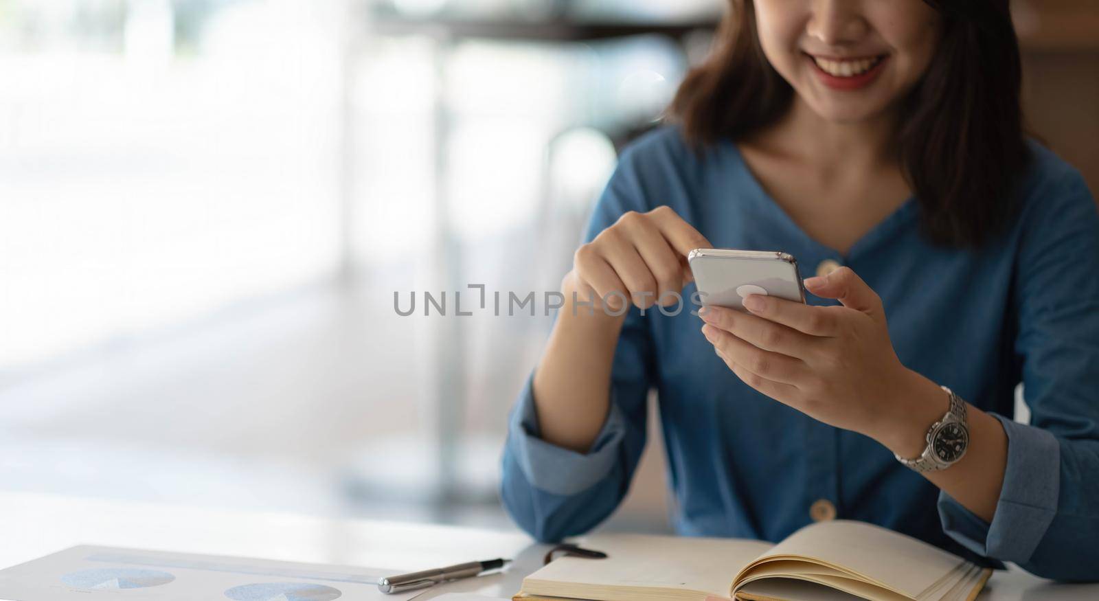 Business asian woman using smartphone for do math finance on wooden desk in office, tax, accounting, financial concept by wichayada