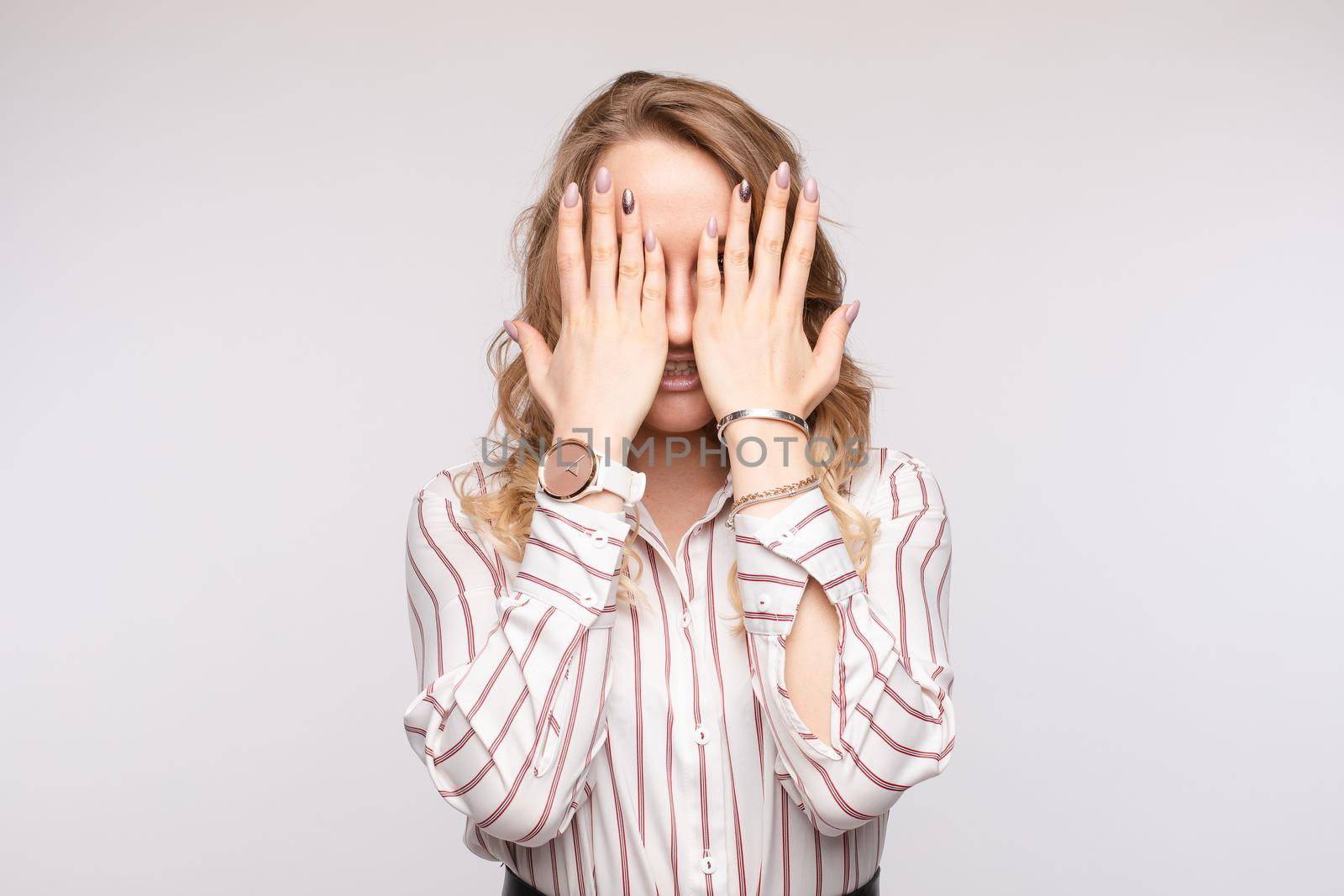 Fashion casual business woman posing closing face by hand isolated at white studio background medium shot. Scared young European female touching eyes by arm and open mouth having stress