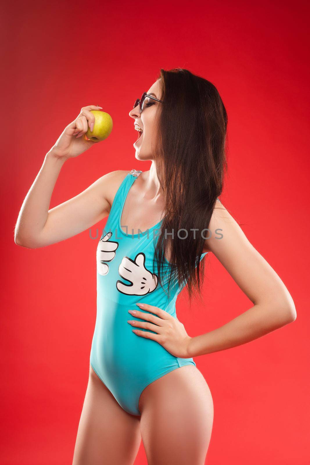 Beautiful girl with tied on back hair eating tasty apple. by StudioLucky
