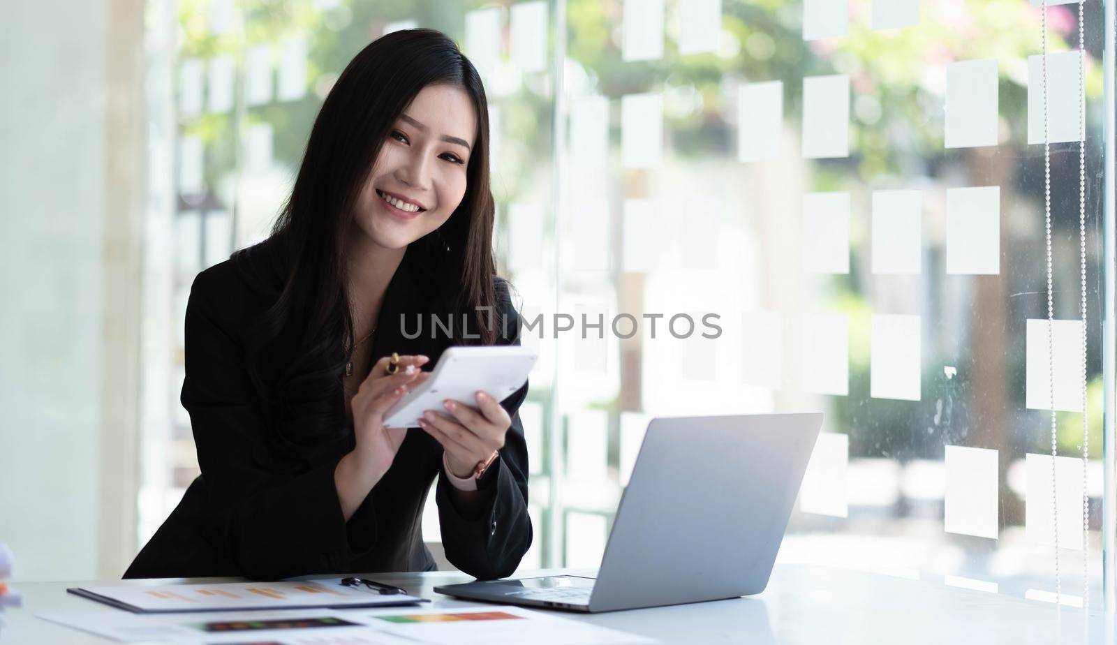 Businesswoman hands hold calculator with financial statistic stock photo,discussion and report analysis data the charts and graphs. Finance concept by wichayada