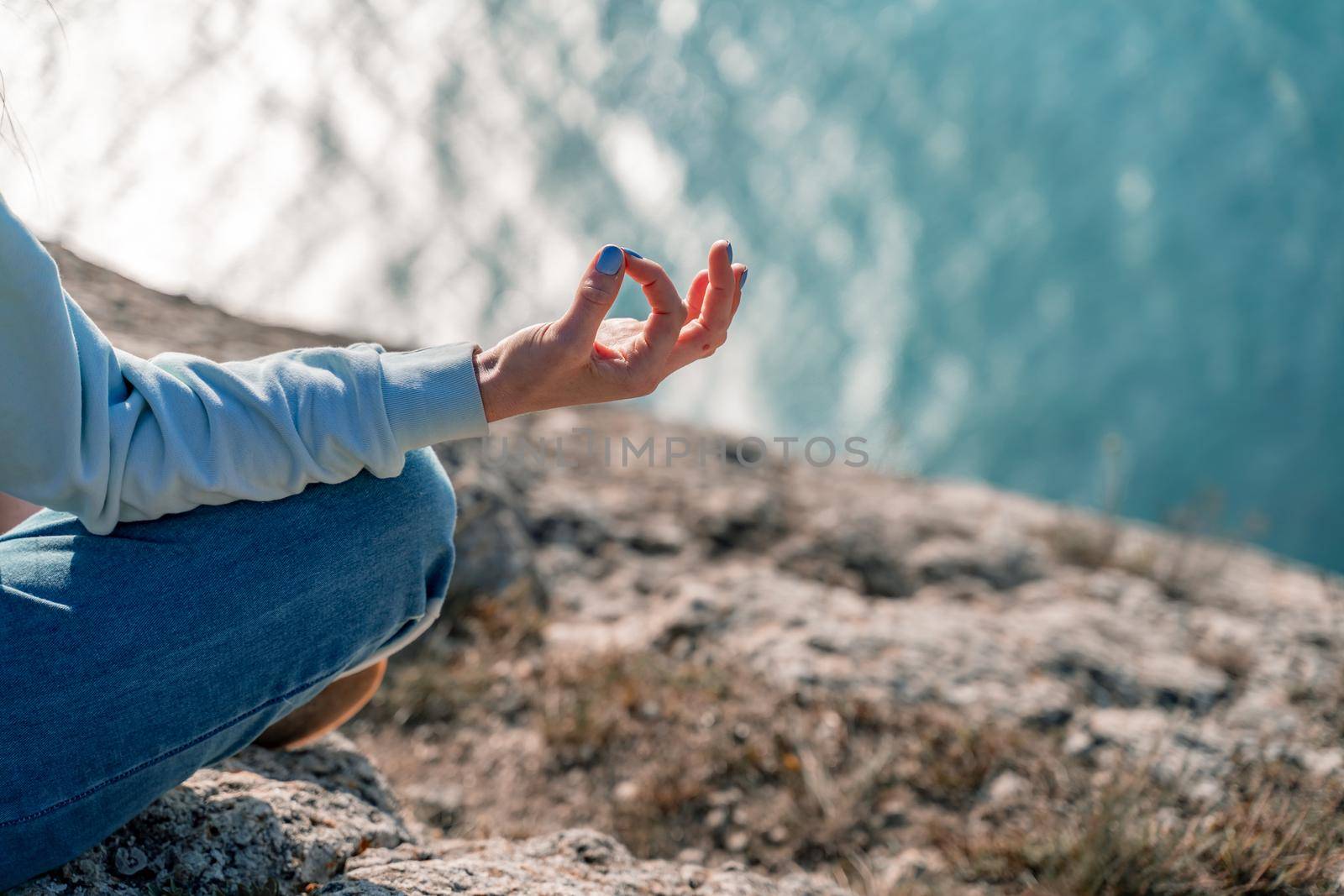 yoga, gesture and healthy lifestyle concept - hand of meditating yogi woman showing gyan mudra over sea sunset background by Matiunina