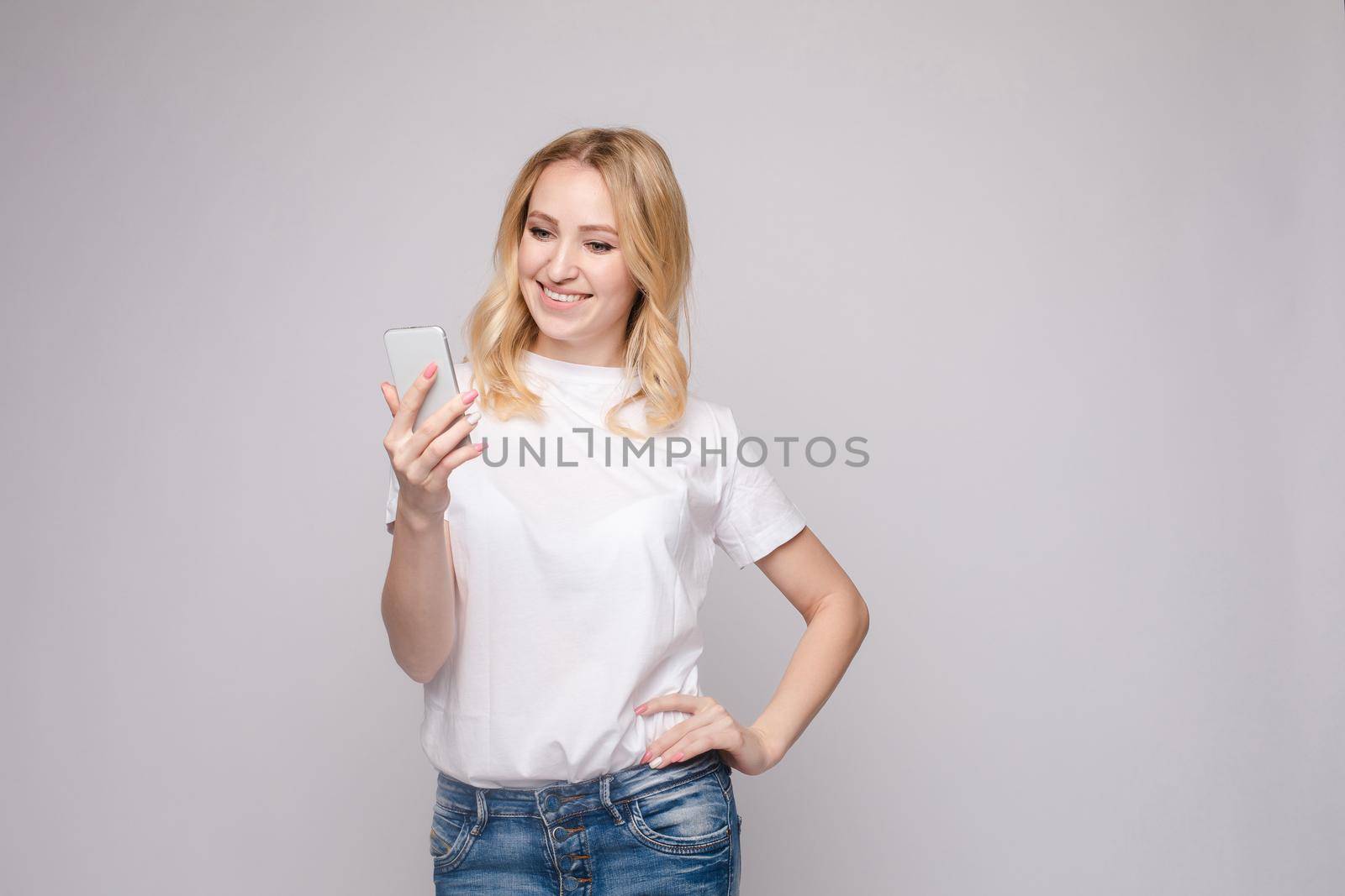 Studio portrait of beautiful caucasian brunette woman in patterned overall pointing at her smartphone with index finger. She is certain or sure about something. I know gesture.