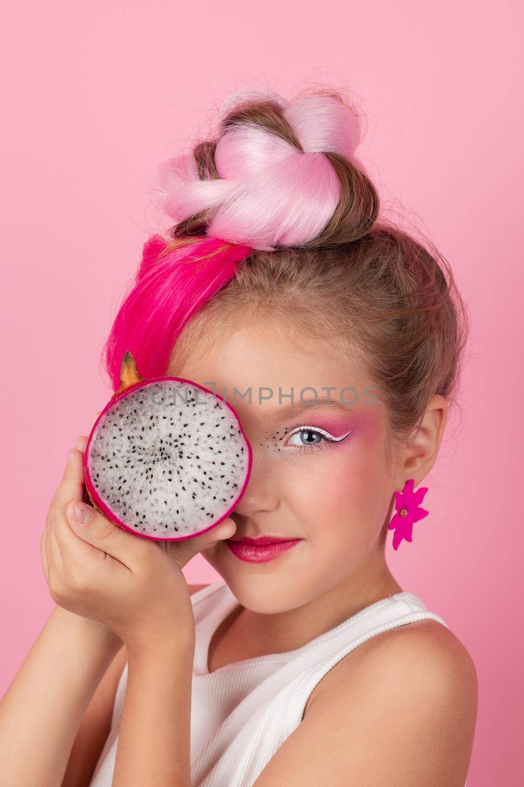 sweet Girl is holding a Pitahaya near her face. A pitaya fruit hold in hand on pink background. Tropical Dragon Fruit cut in half. space for text. by oliavesna