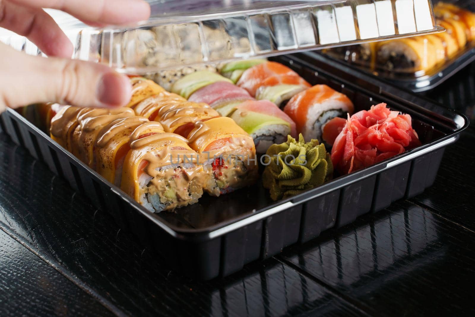 Sushi roll food delivery service. Sushi set in box on black background. Traditional Japanese seafood. Delicious roll.