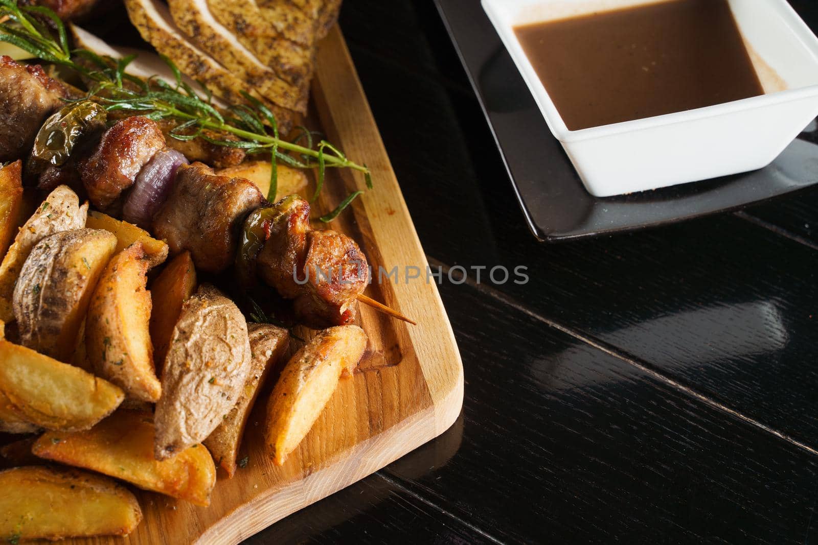 Pork kebab. Barbecue tasty meat ot the black plate. Potato, meat, and sausages by Rabizo