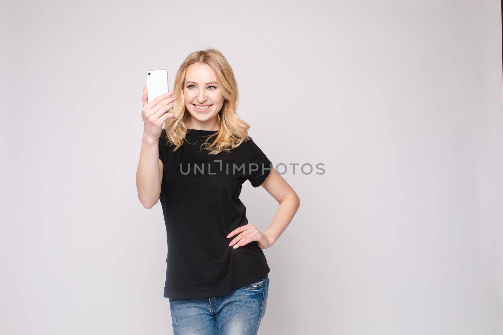 Studio portrait of beautiful caucasian brunette woman in patterned overall pointing at her smartphone with index finger. She is certain or sure about something. I know gesture.