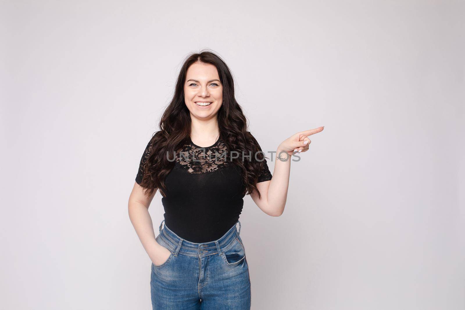 Pretty girl pointing at cell phone.Studio portrait of beautiful caucasian by StudioLucky