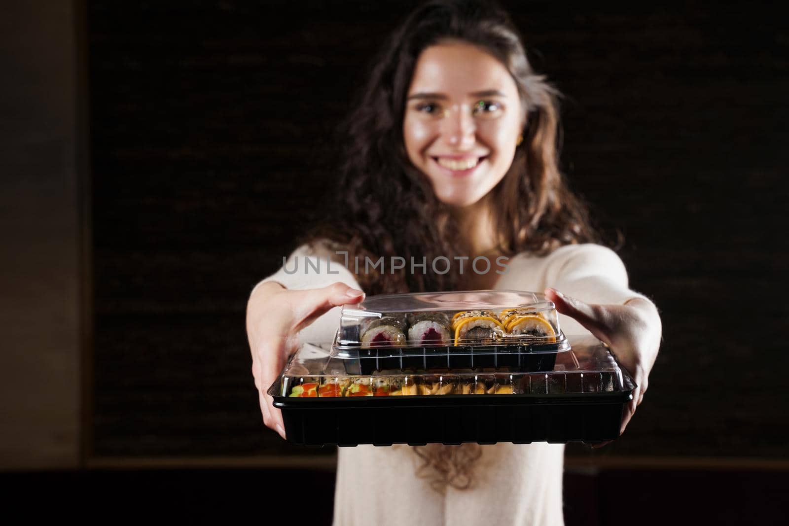 Sushi in box healthy food delivery online service. Girl holds 2 sushi sets in hands. Japanese cuisine: rolls, soy sauce, wasabi