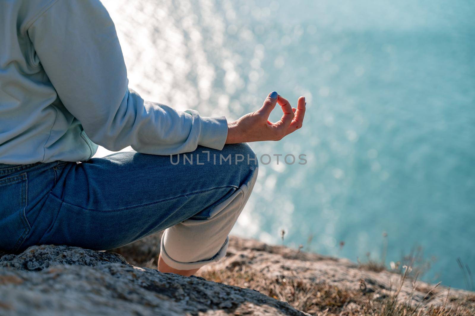 yoga, gesture and healthy lifestyle concept - hand of meditating yogi woman showing gyan mudra over sea sunset background by Matiunina