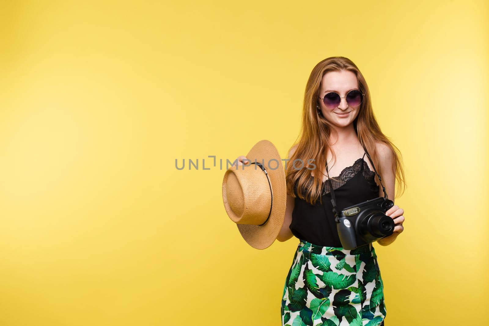 Young girl in straw hat and glasses keeping camera by StudioLucky