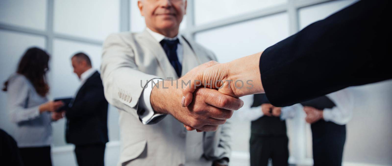 businessman confidently shaking hands with his business partner. by SmartPhotoLab