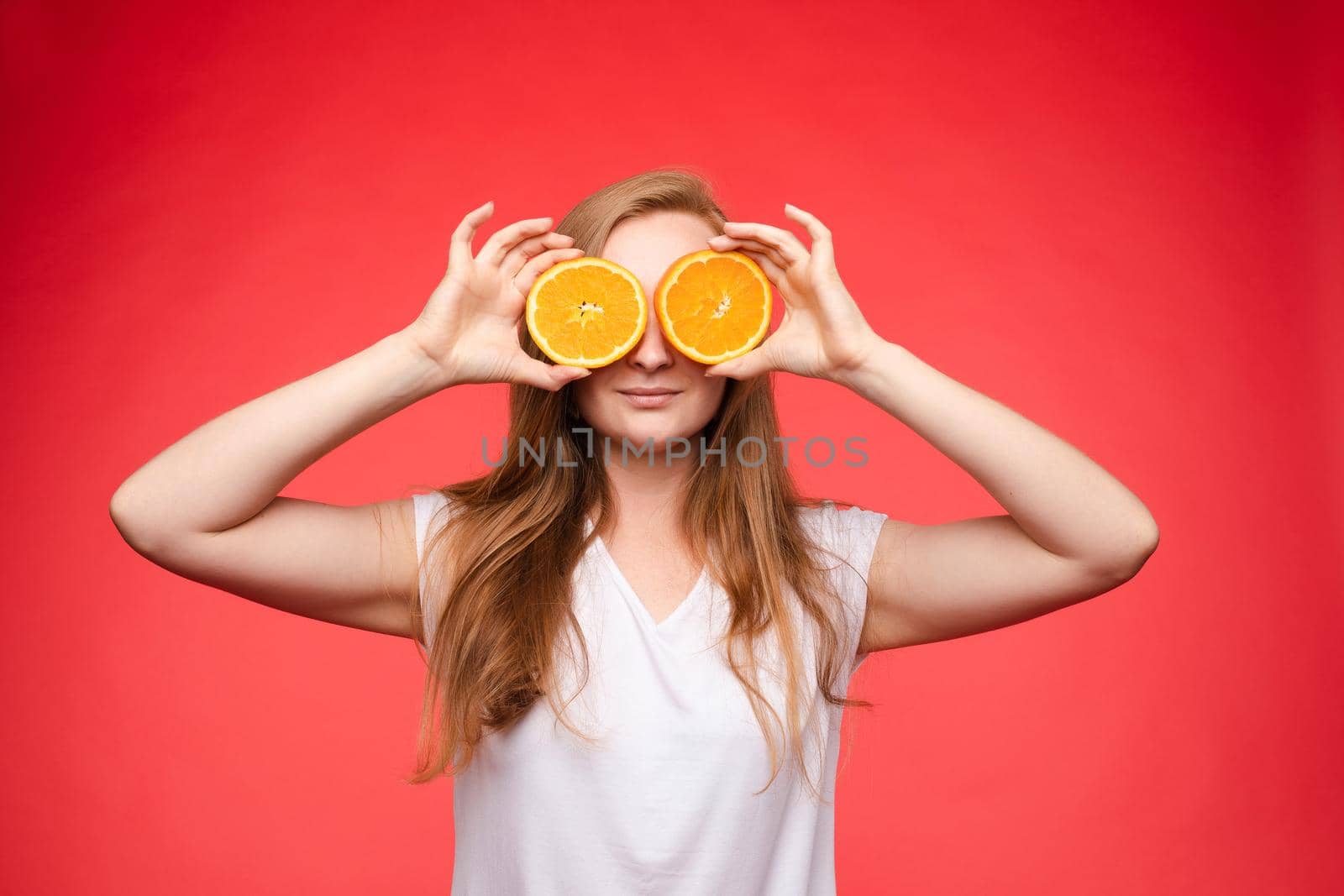 Funny fashionable girl with hairstyle holding oranges on eyes. by StudioLucky