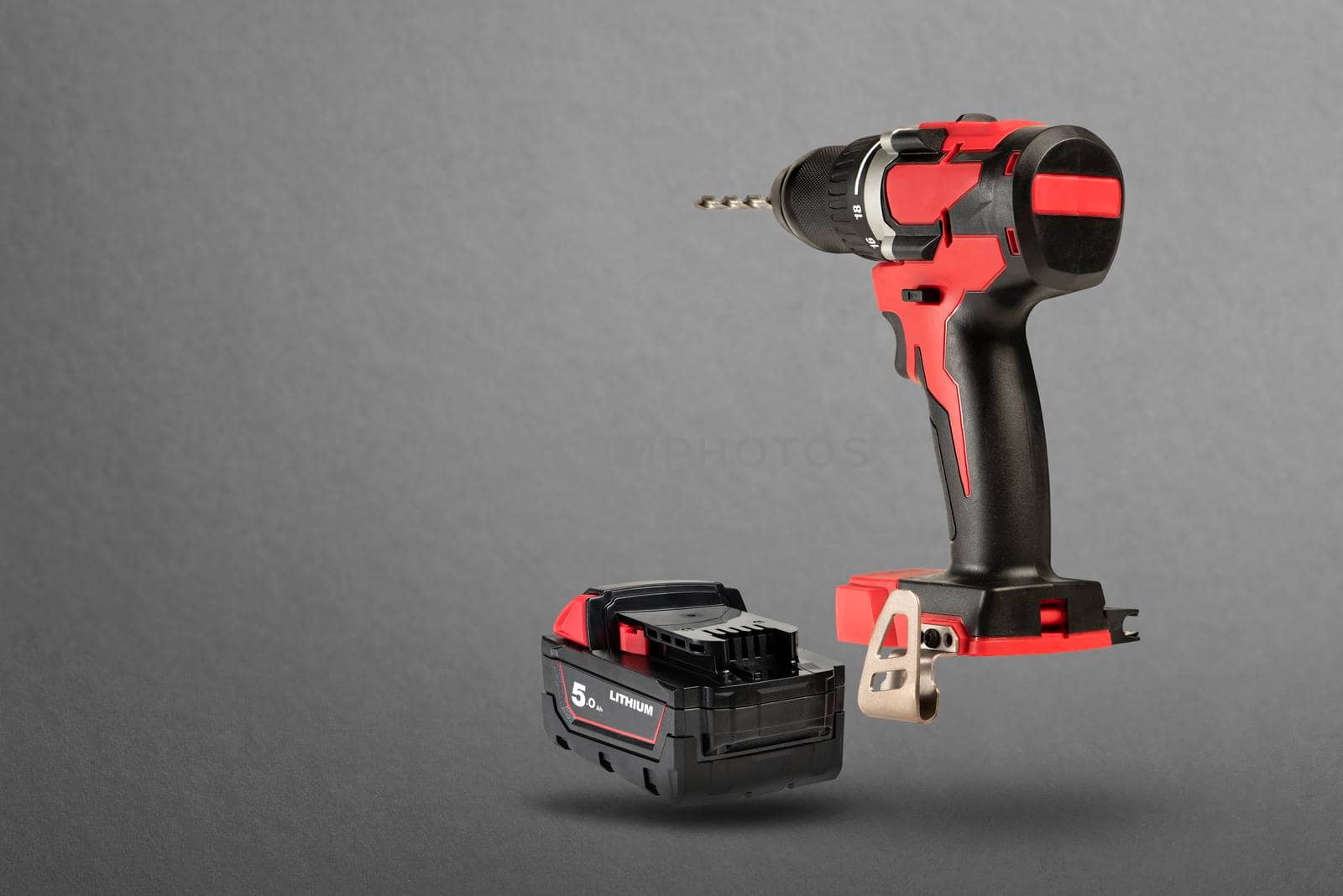 Wireless tools. Cordless drill with drill bit. The screwdriver with the battery removed falls, casting a shadow. Advertising banner of construction or industrial theme on gray background.