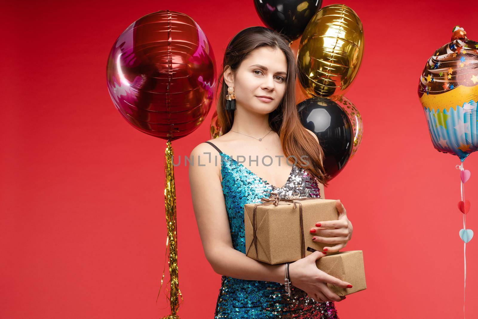 Full length studio portrait in sexy sparkling cocktail dress with red lips. She is posing with lips air balloon. Isolate on red background.