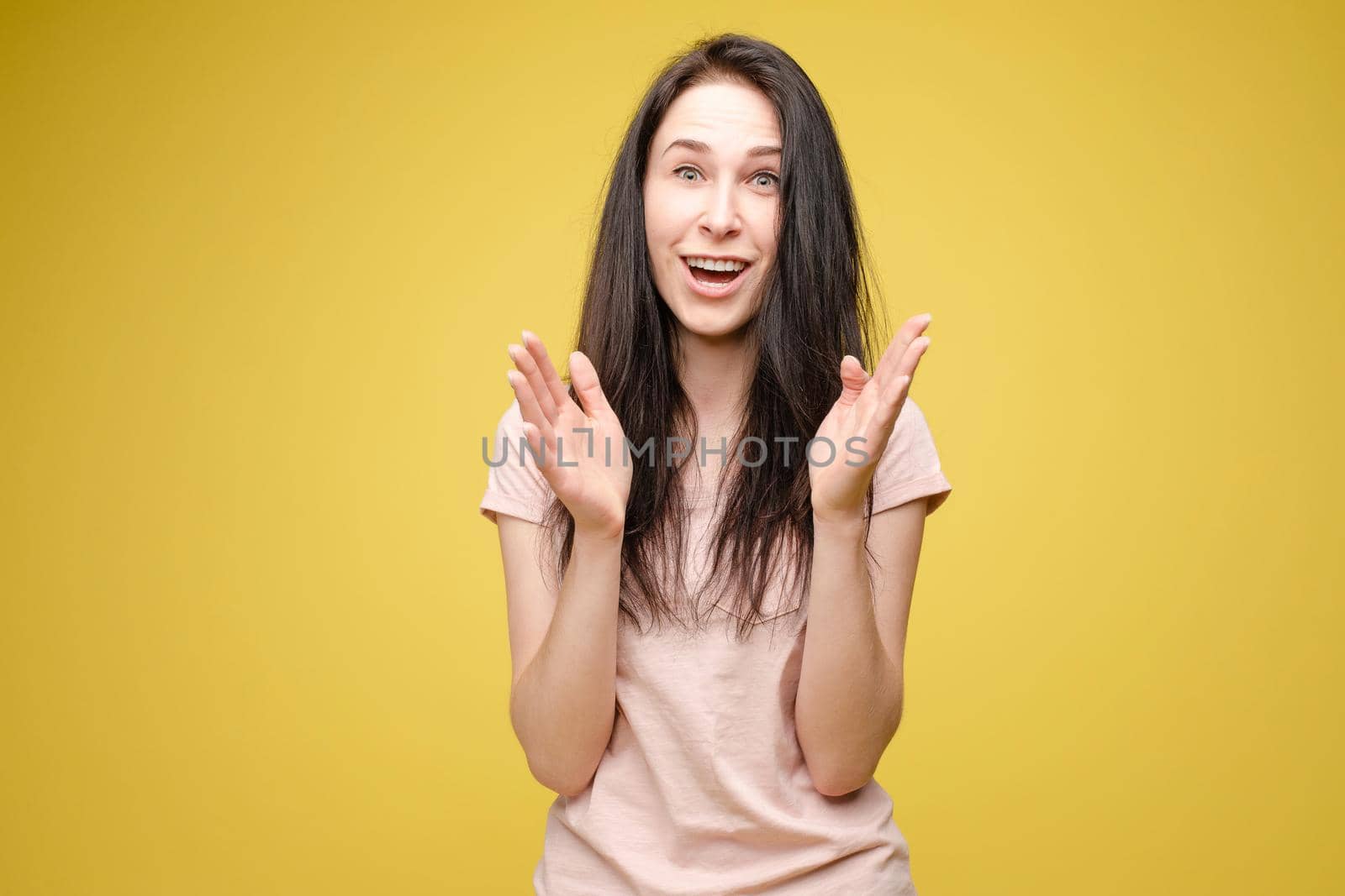 Surprised young girl on yellow isolated background in studio by StudioLucky