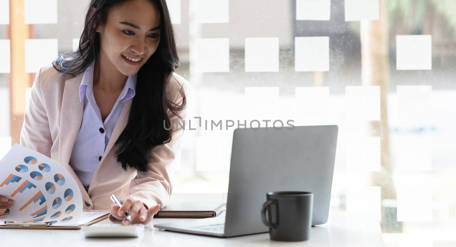 Charming asian businesswoman sitting working on laptop in office..