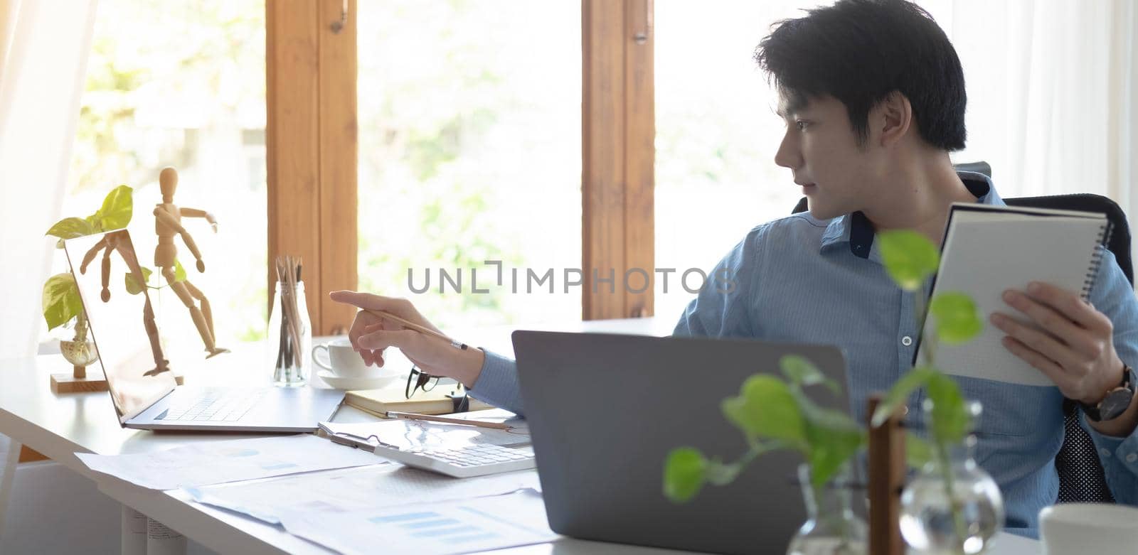 Portrait of Young Asian man hand freelancer is working her job on computer tablet in modern office. Doing accounting analysis report real estate investment data, Financial and tax systems concept. by wichayada