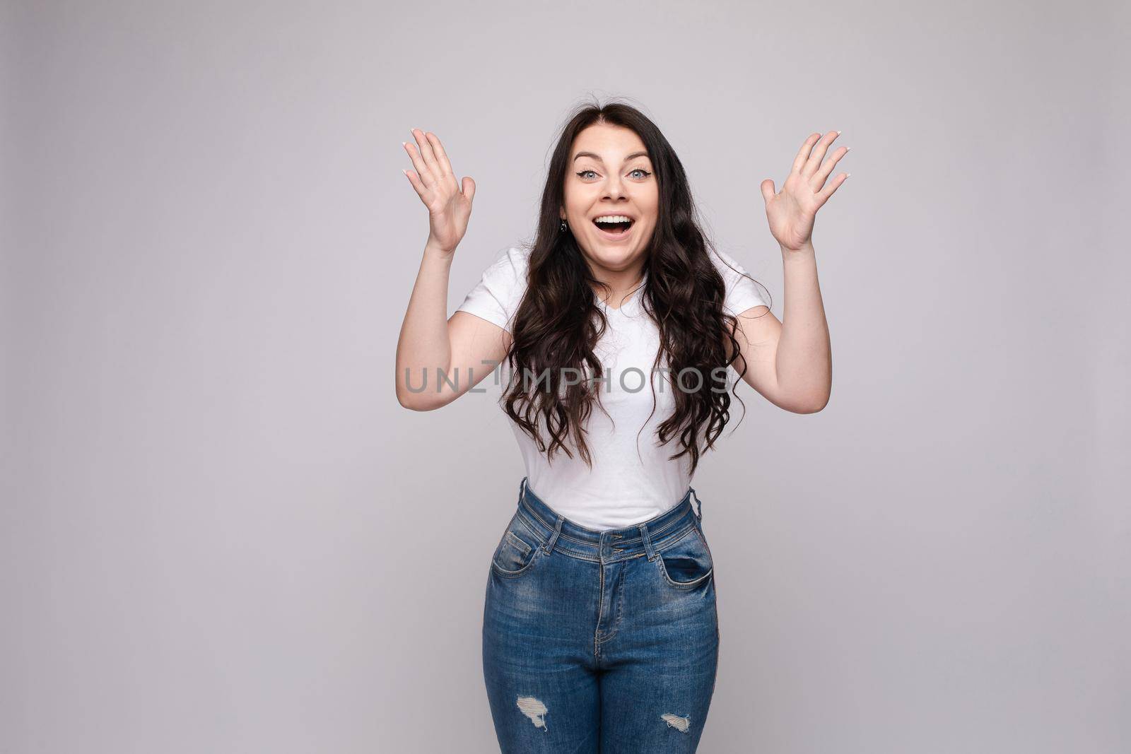 Waist up portrait of surprised beautiful girl with nice long hair, perfect makeup and fashion manicure. She is looking at camera with astonishment. Isolated