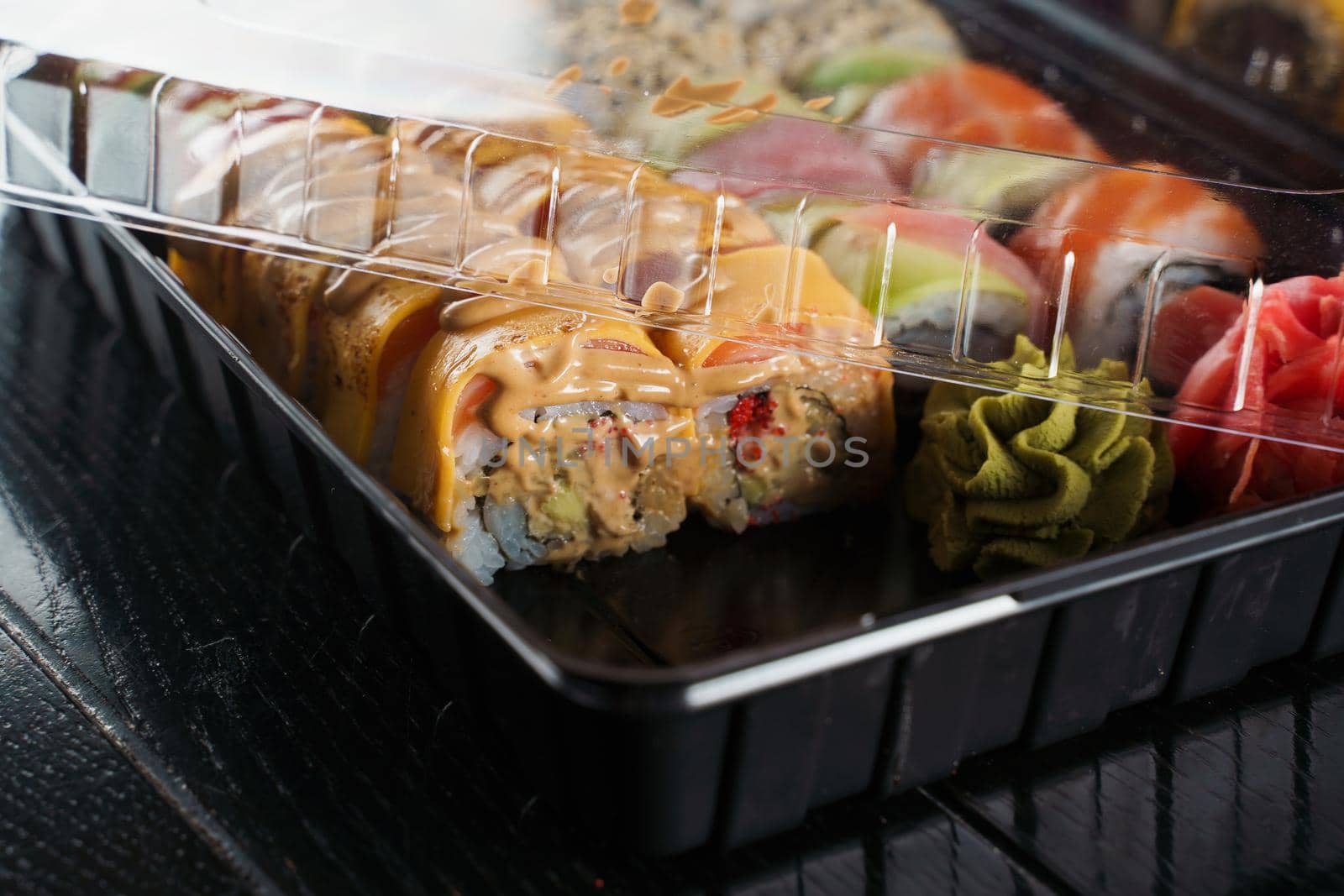 Sushi roll food delivery service. Sushi set in box on black background. Traditional Japanese seafood. Delicious roll.