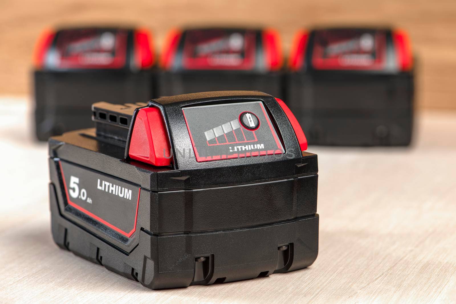 Battery for cordless drill. Screwdriver battery. Four batteries with a charge indicator lie on a wooden background.