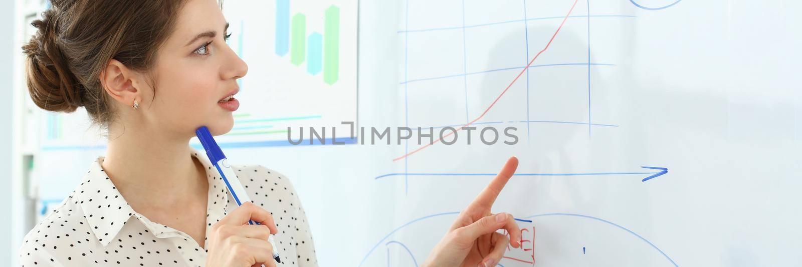 Portrait of attractive manager working in big modern office and discussing important graphs with witty colleagues. Smart woman pointing at complicated charts. Company meeting concept