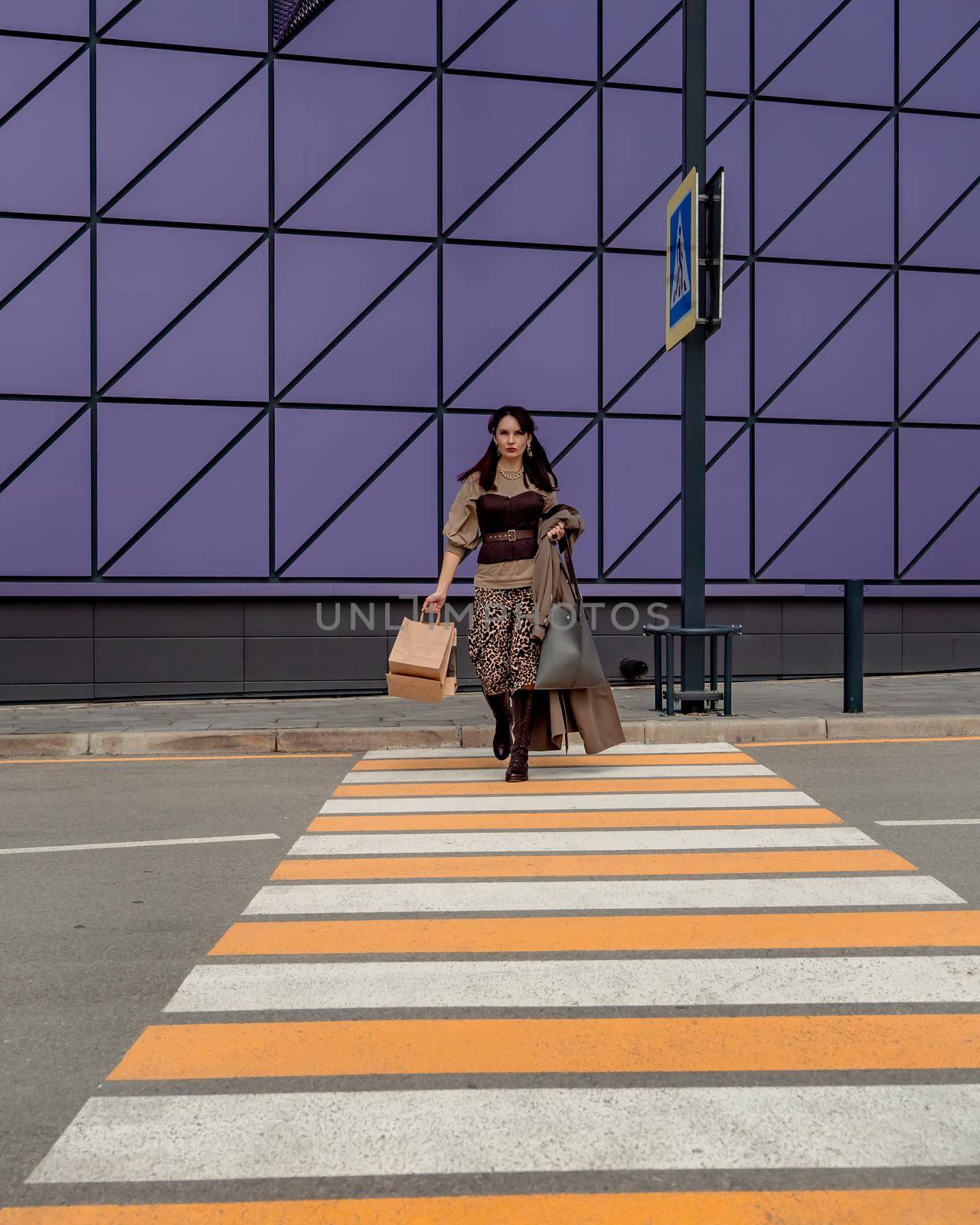 A beautiful girl with shopping bags is walking along a pedestrian crosswalk. Consumerism, shopping, shopping, lifestyle concept by Matiunina
