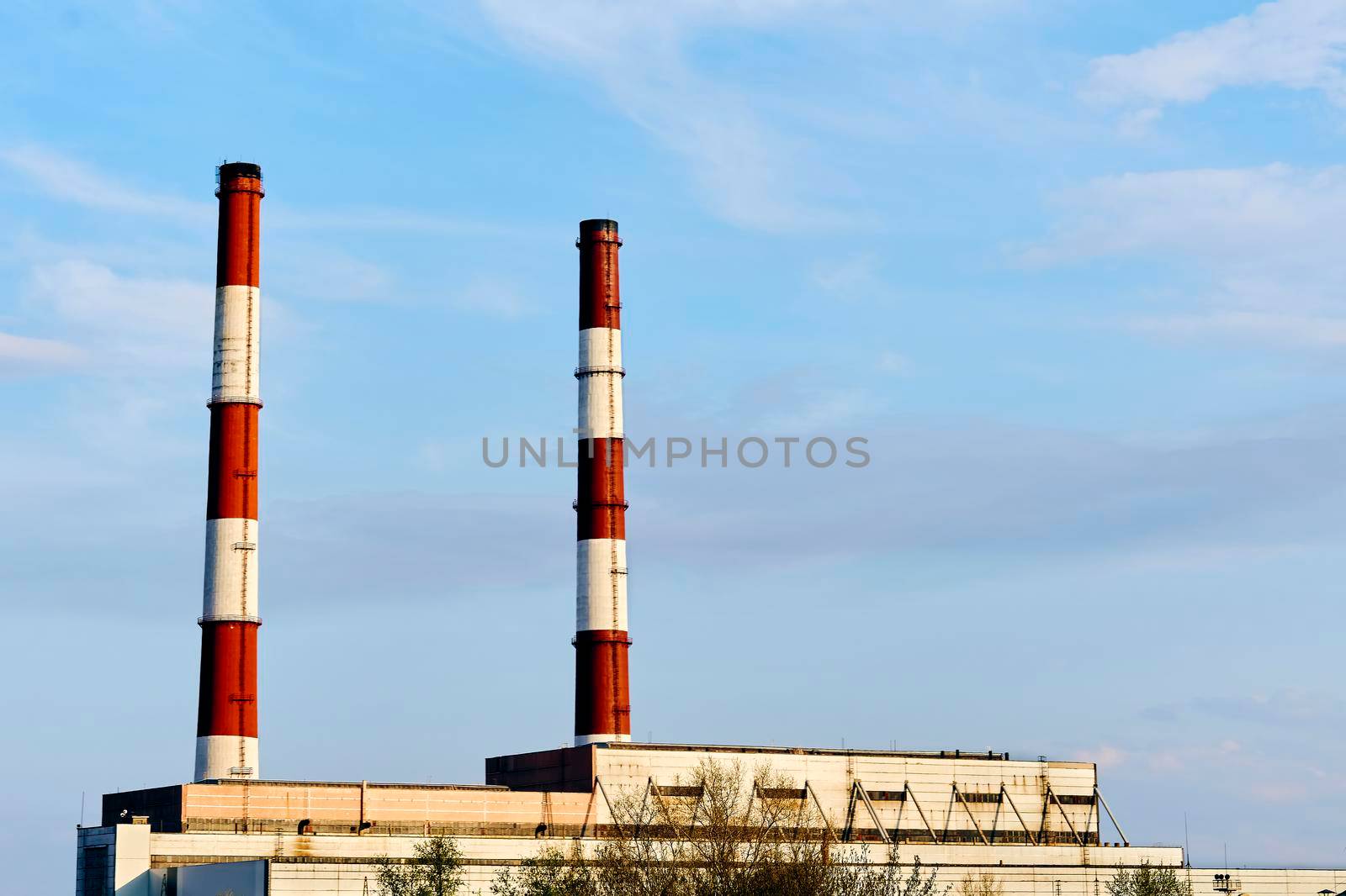 a building or group of buildings where goods are manufactured or assembled chiefly by machine.Two factory pipes of a thermal power plant against the blue sky.