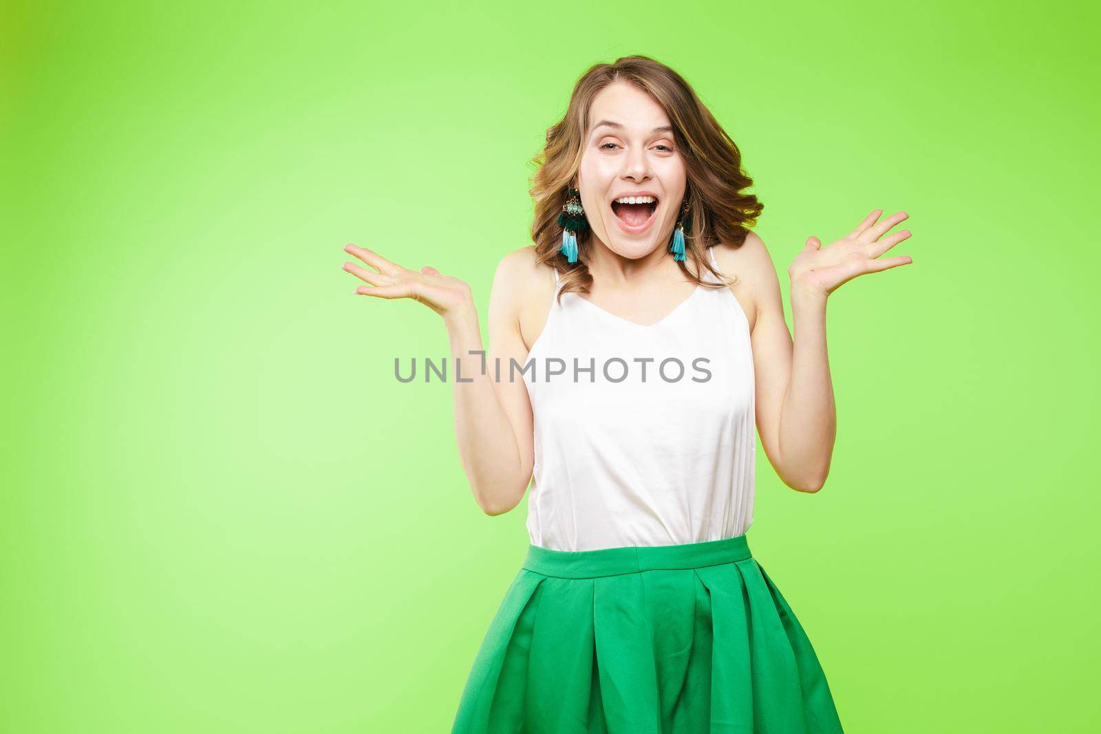 Studio portrait of attractive young caucasian brunette in casual outlook covering her mouth in shock or astonishment. She is shocked, stupified or surprised. Looking at camera with shocked facial expression on yellow background.