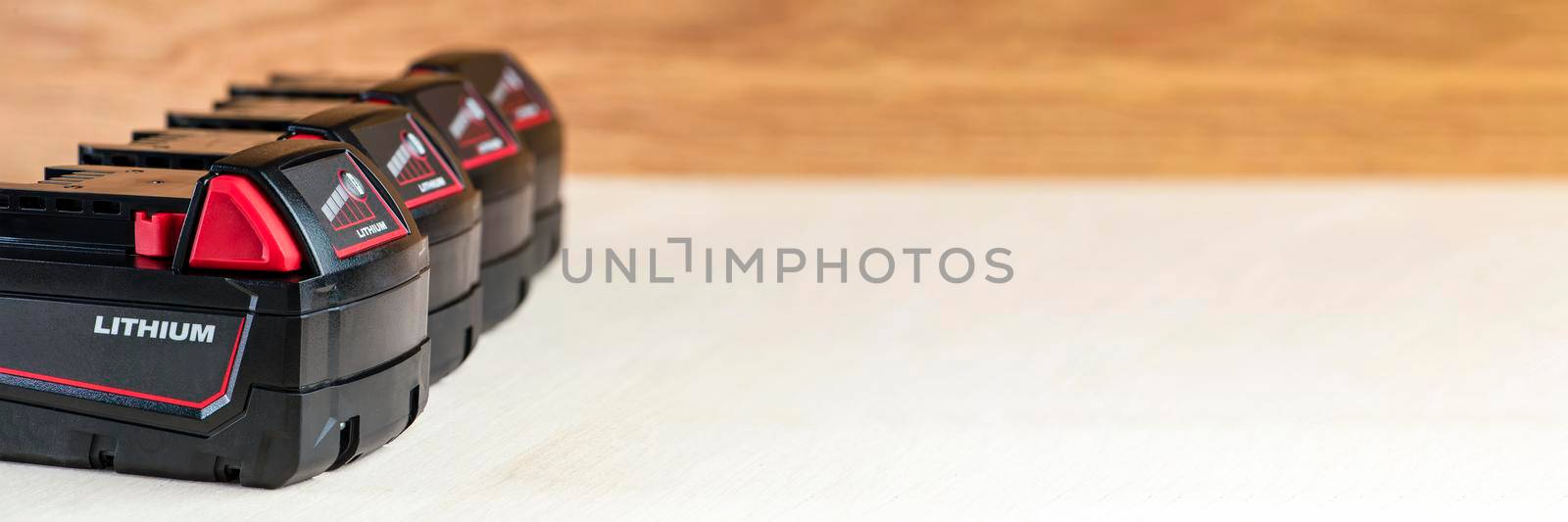 Four batteries for a screwdriver lie on a wooden background. Batteries for cordless tools with charge indicator by SERSOL