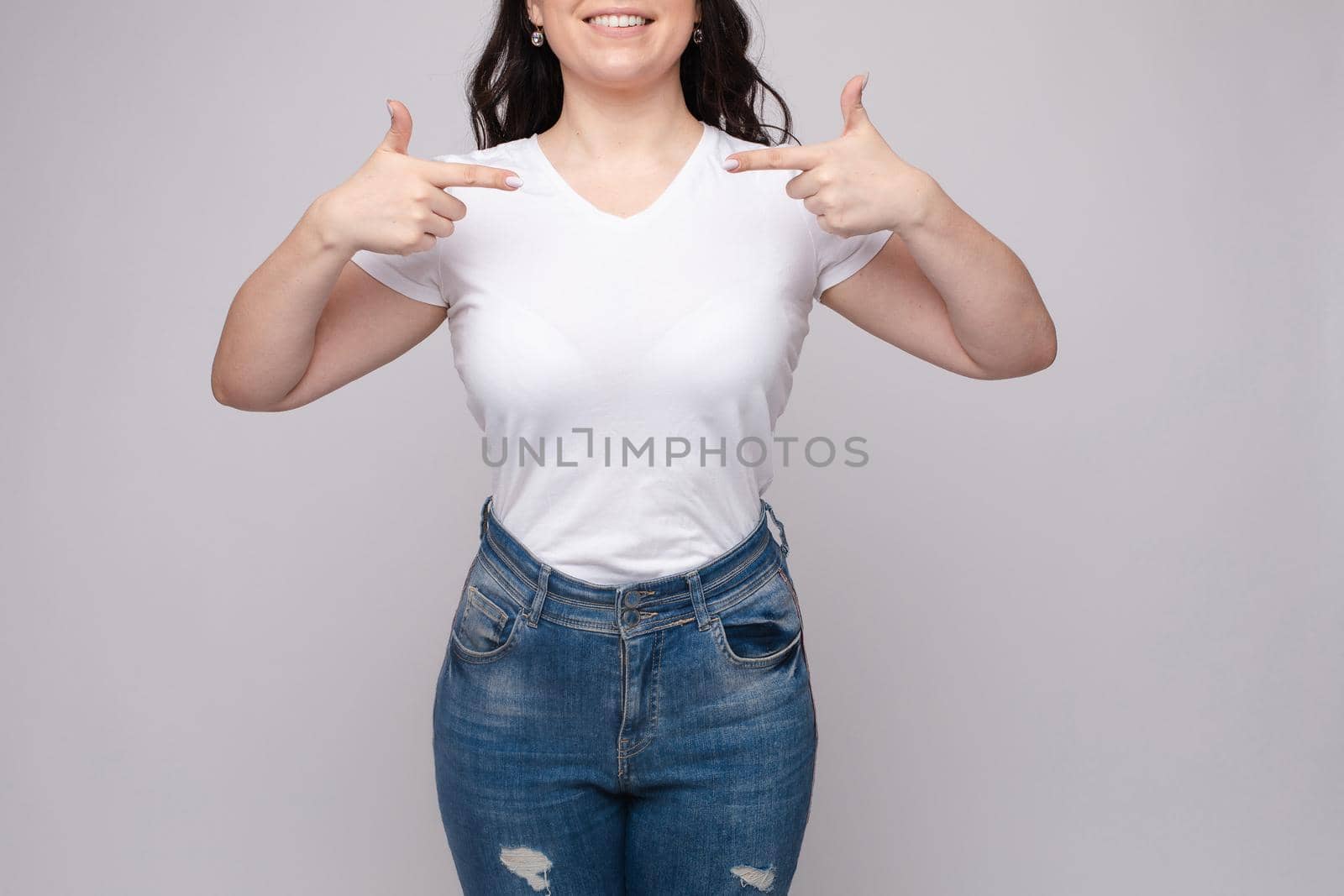 Cropped view of brunette standing in white shirt and jeans by StudioLucky