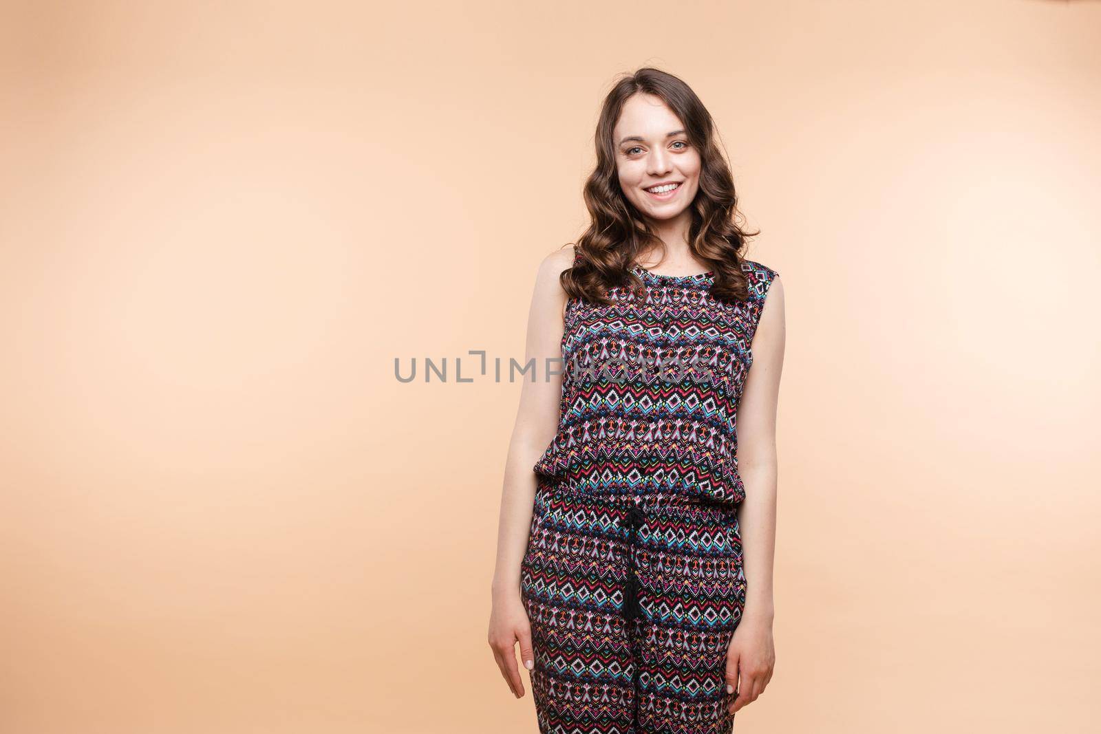 View from front of beautiful slim woman standing steady on frey isolated background. Young looking at camera, smiling and posing in studio.