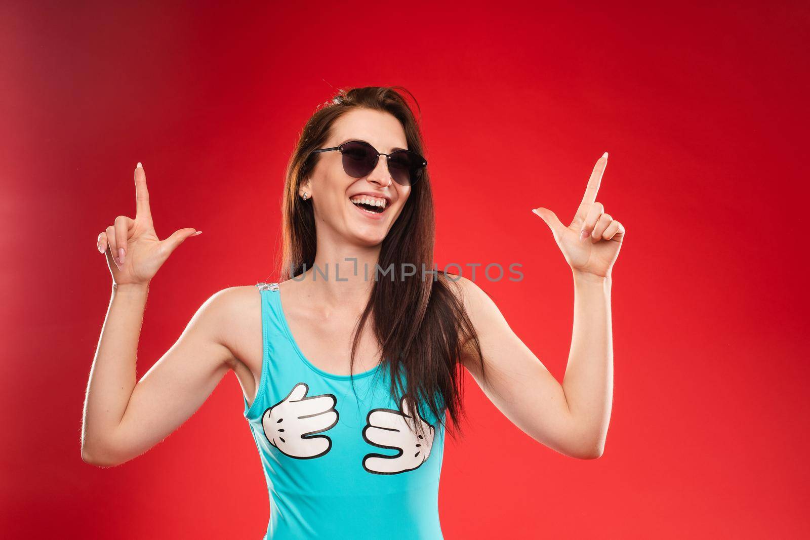 Side view studio portrait of stylish attractive young woman looking away and holding finger. Sudactive feminine model in black with make up plump lips and big eyes holding hand. Concept of style.