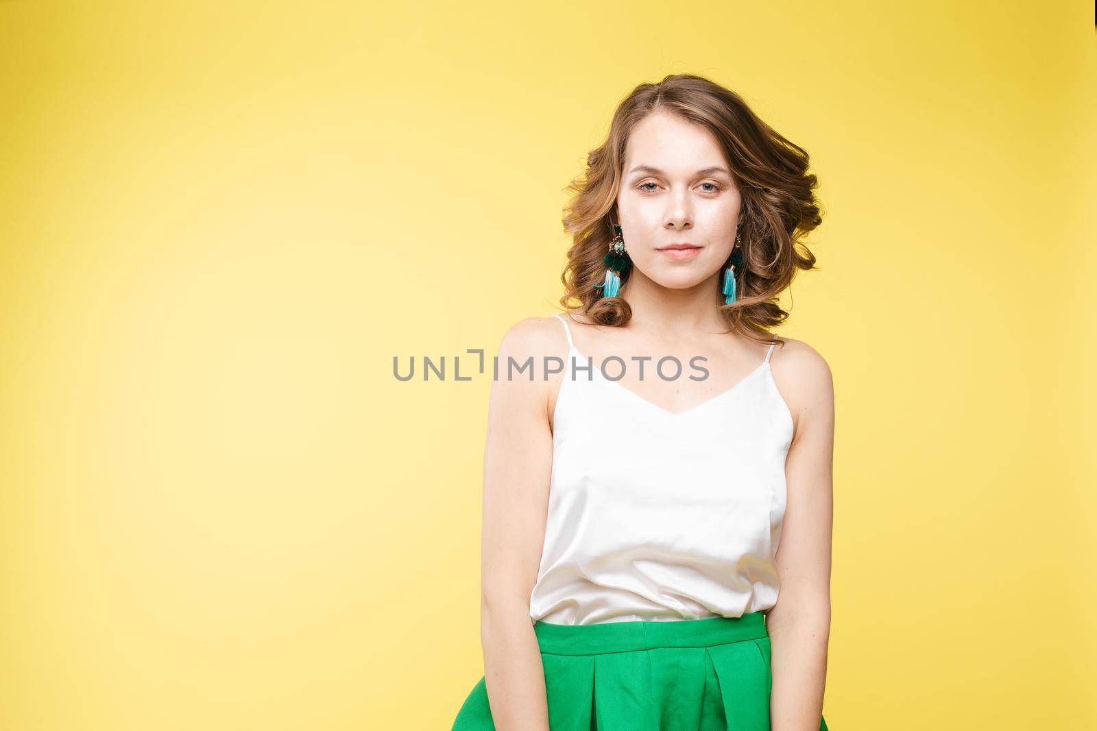 View from front of beautiful slim woman standing steady on frey isolated background. Young looking at camera, smiling and posing in studio.