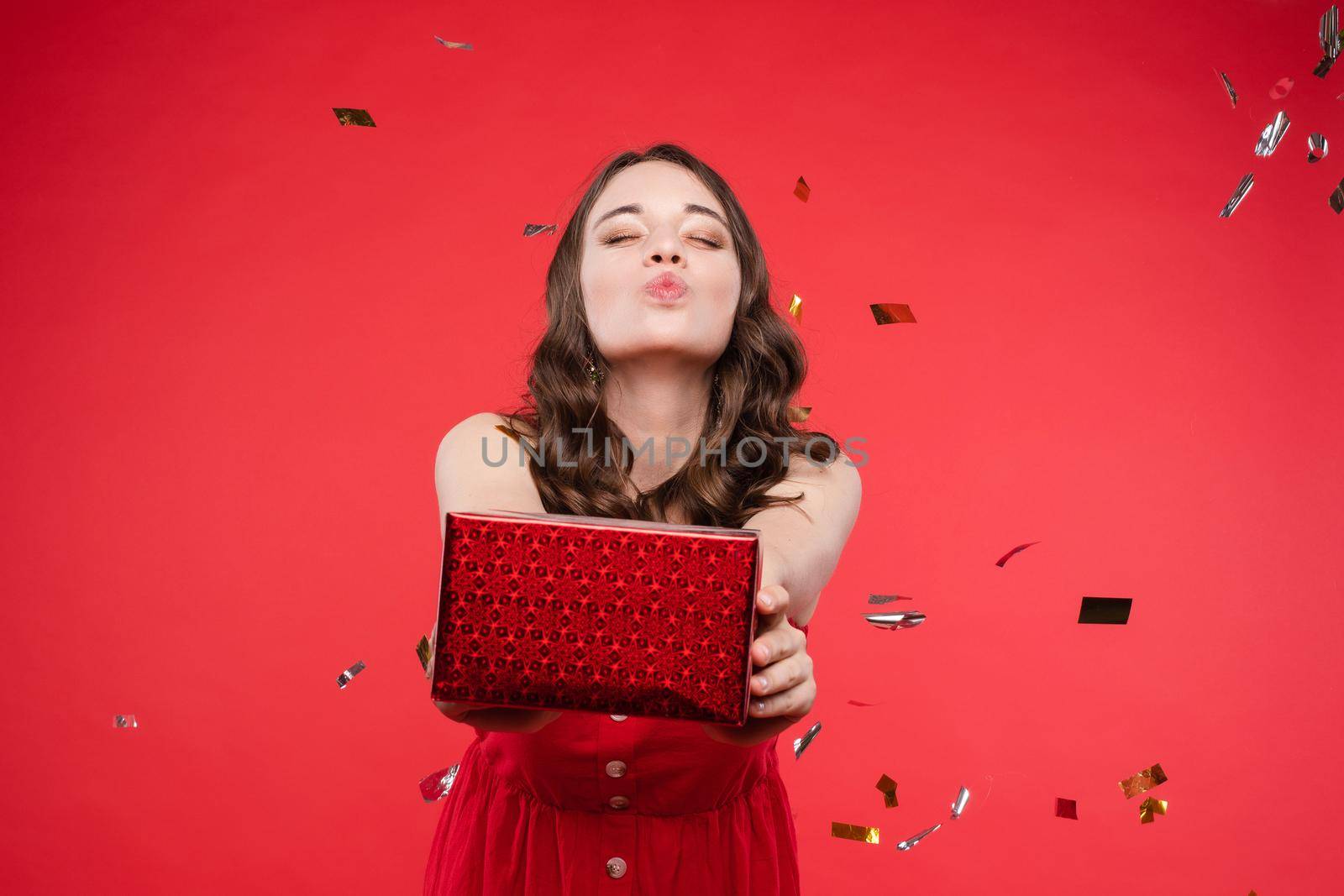 Brunette in red dress posing while sparkles falling around by StudioLucky