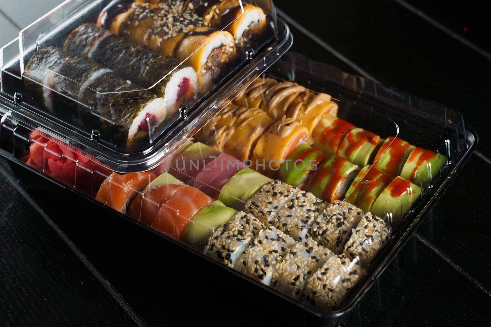 Sushi roll food delivery service. Sushi set in box on black background. Traditional Japanese seafood. Delicious roll.