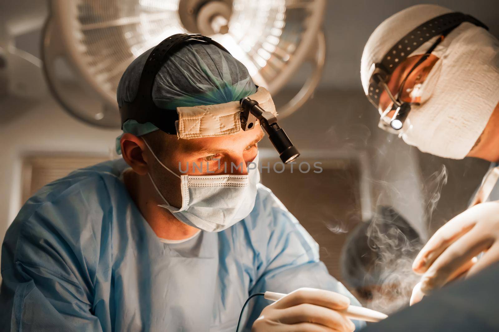 2 surgeons with headlamp do plastic operation in medical clinic. Chest augmentation plastic operation and correction in medical clinic