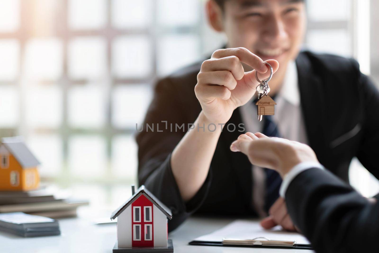 estate agent giving house keys to woman and sign agreement in office by wichayada