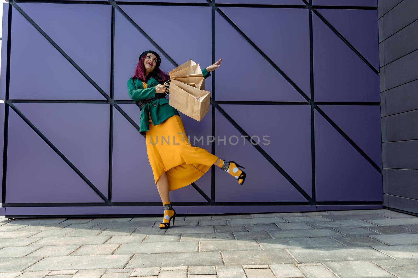 A happy shopaholic girl throws her bags near a shopping center. Have fun shopping on Black Friday. the girl in the store is happy with her purchases, throws packages. Consumer concept. by Matiunina