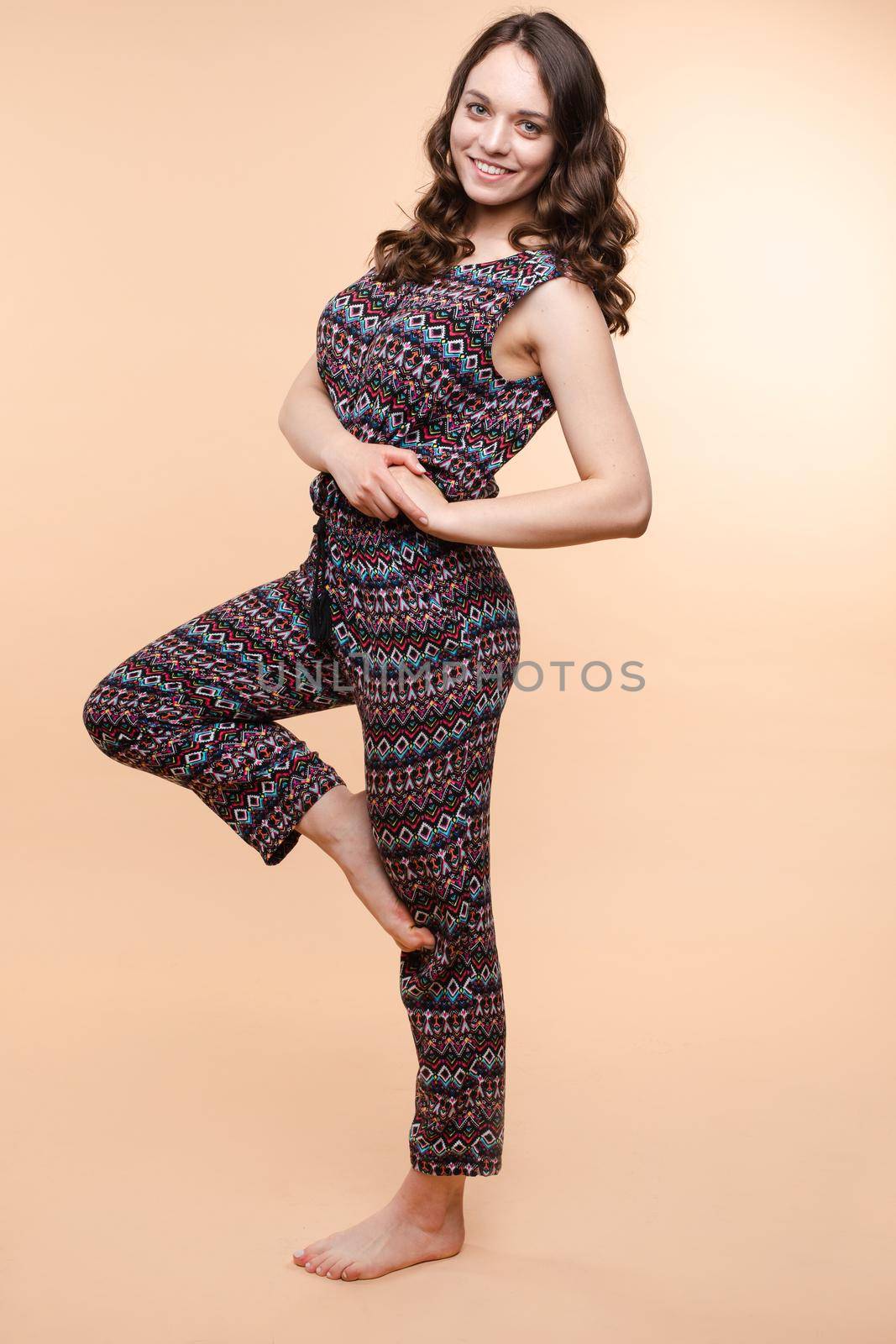 View from front of beautiful slim woman standing steady on frey isolated background. Young looking at camera, smiling and posing in studio.