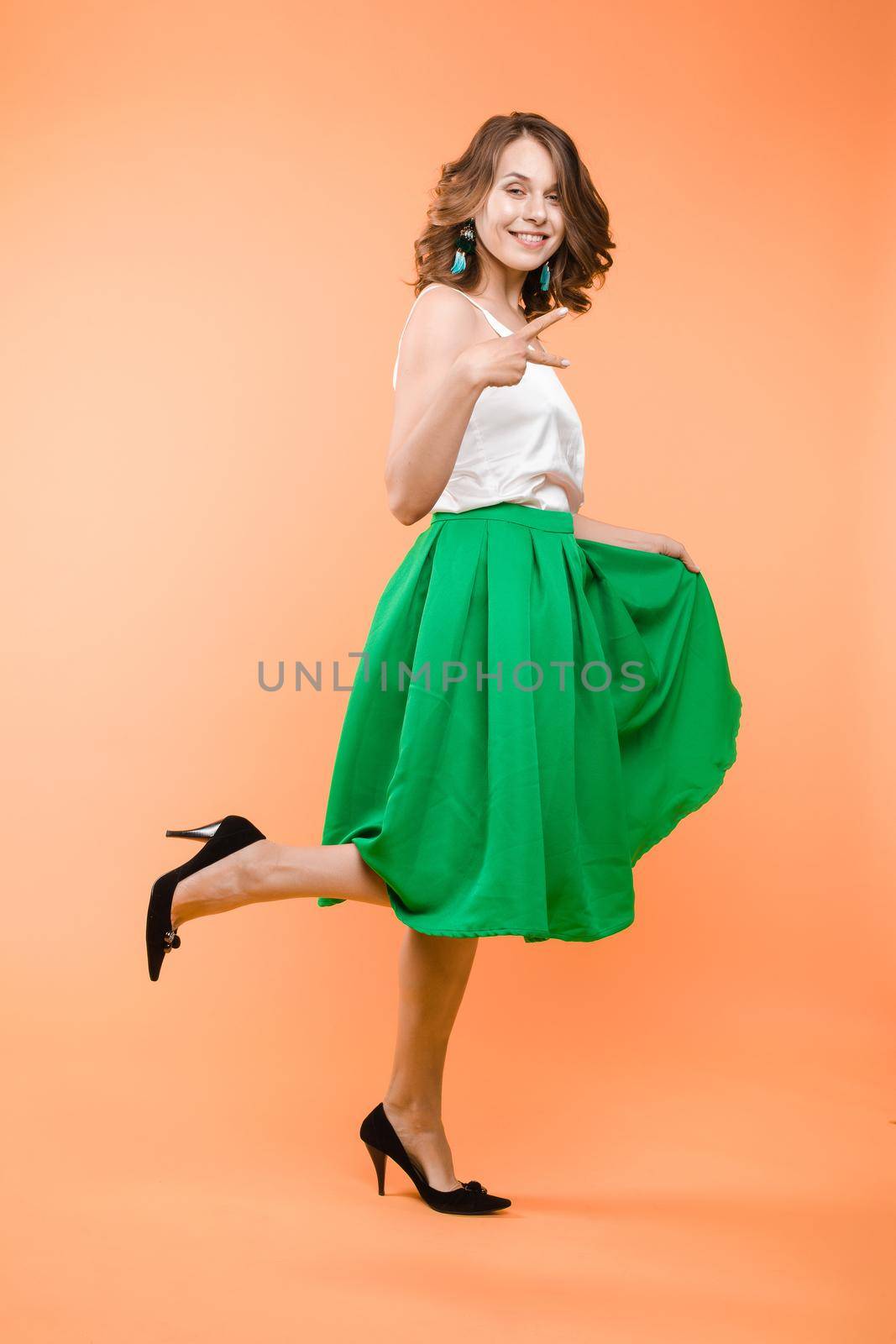 View from front of beautiful slim woman standing steady on frey isolated background. Young looking at camera, smiling and posing in studio.